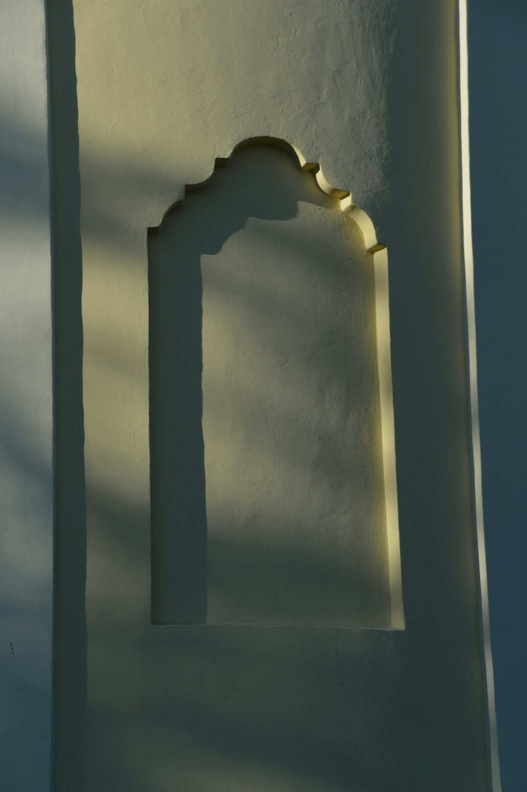 Tall pale wall with a single doorway of light